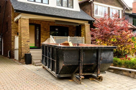 A roll-off construction dumpster outside a residential renovation project in an older neighourhood. shot in toronto in the fall