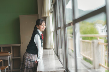 教室で窓の外を見る日本人の女子中学生