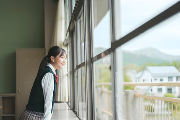 Fototapeta premium 学校の教室の窓の外を見る日本人の女子中学生