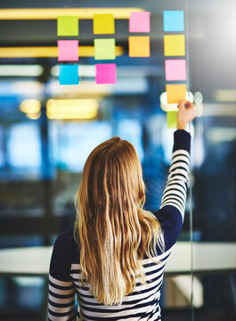 Back, creative and woman with notes on glass wall for planning, future ideas and schedule session. Thinking, girl and reading mind map with information list, presentation agenda and project timeline