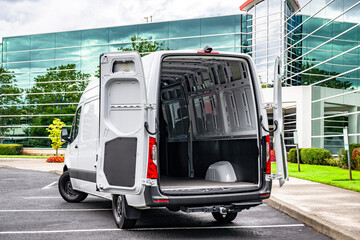 Light duty white cargo mini van make delivery to the business place and standing with open rear doors on the marked parking lot © vit