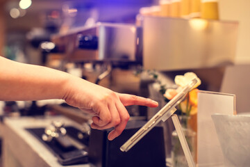 Cashier staff using tablet to receive orders from customers at counter service in cafe or store. Cashier takes payment from customer with digital tablet.