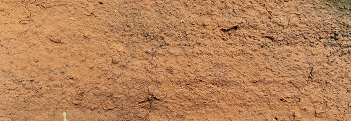 Close-up view of red soil with cracks and a rough texture. Premium classic wall background photo for banner background or wallpaper.