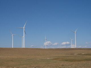 Group of Wind Turbines in a Prairie with Blue Sky and Scattered Cumulus Clouds