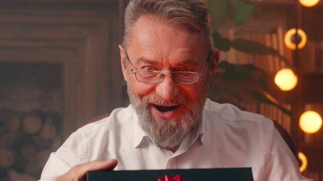 Happy old Caucasian man male home office business businessman elderly opening box celebrate present prize gift birthday unpacking surprise excited unbox inside handsome purchase order mature pensioner