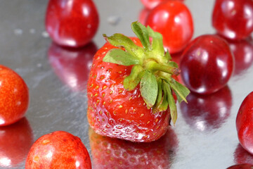 Strawberries and Cherries on gray background. Many fresh juicy strawberries