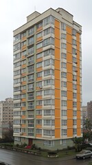 Tall residential building with colorful facades in a bustling urban area on a cloudy day