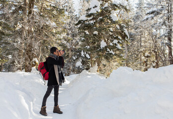 photographer man standing and take a photo in winter forest in Shinhotaka,Japan