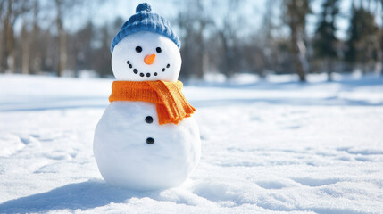 Obraz premium Snowman wearing blue hat and orange scarf in winter snow. Perfect for winter holidays and celebration.