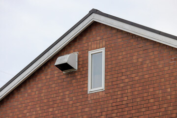 三角形の屋根の家の換気口と縦長の窓