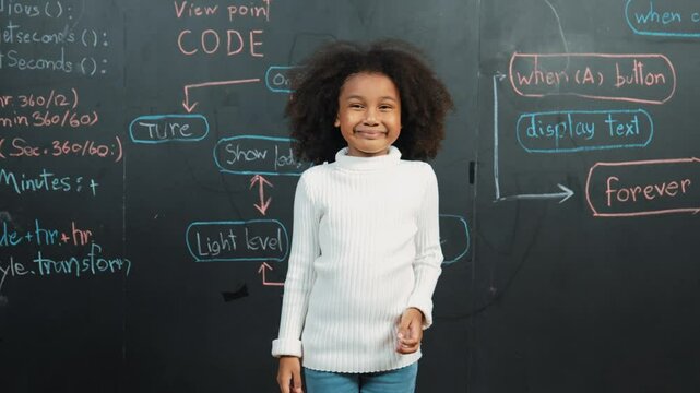 Happy african student smiling and standing at board with engineering prompt or coding, programing system written in STEM technology classroom. Child present science theory or innovative. Erudition.