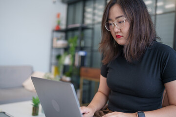 concentrated Asian woman using laptop computer creative girl working and typing on keyboard