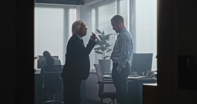 In modern office of bank: Irritated and angry boss having fight with male company employee over unsuccessful business deal. Senior team leader with papers loses temper and yells at man. Slow Motion.