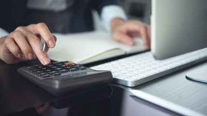Close up business woman hand using calculator to calculate home finance and writing note,...