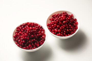 Two bowls of lingonberries on a white background