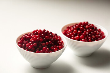 Two bowls of red lingonberries on a white background