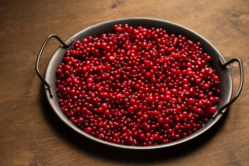 A vintage metal tray full of lingonberries on a wooden background