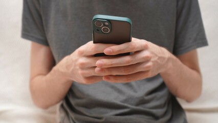 Hands of a young man sending a message via mobile phone on a smartphone