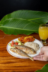 Exquisite Colombian dish with fish, coconut rice, salad and plantain with orange juice on a wooden table. Colombian gastronomy, typical dish.
