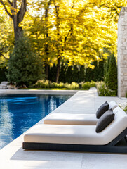 Obraz premium Relaxing poolside loungers under golden autumn trees in a serene backyard setting