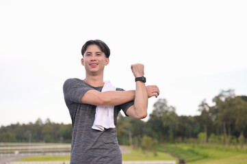 Relaxed asian man stretching muscles after jogging in the park