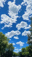 Obraz premium Bright, fluffy white clouds scattered across a vibrant blue sky on a perfect summer day