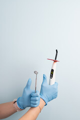 Dental professional holds curing light and mirror tools in a bright clinic setting during an appointment