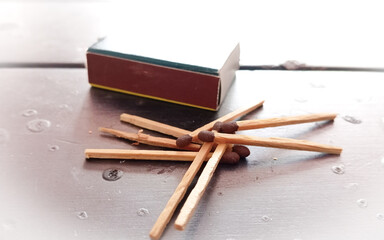 Fits in box, white background. Macro photography. Close-up shot. Match in an open matchbox against a black table background.
