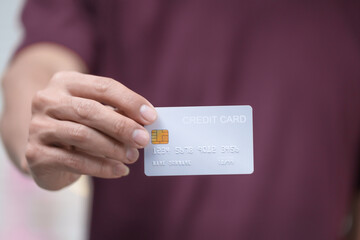Close-up of a man's hand holding a bank credit card, highlighting online services for lending and...