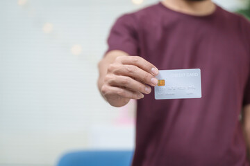 Close-up of a man's hand holding a bank credit card, highlighting online services for lending and...