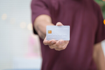 Close-up of a man's hand holding a bank credit card, highlighting online services for lending and...