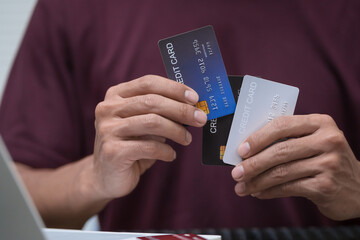 A businessman sits at a table, using his credit card to make an online payment on his laptop. He enjoys a lifestyle of frequent travel, shopping, and smart financial habits for wellness