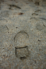 Lonely foot prints remain in the sand covered ground of an empty, rain soaked playground.
