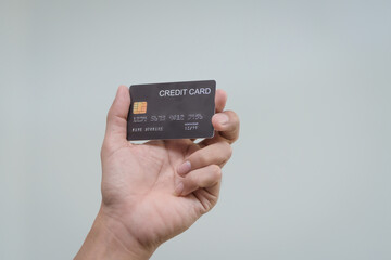 A close-up of a man’s hand holding a bank credit card against a white background, emphasizing secure online payment services and financial convenience for shopping and banking transactions