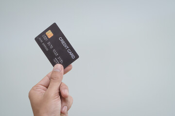 A close-up of a man’s hand holding a bank credit card against a white background, emphasizing secure online payment services and financial convenience for shopping and banking transactions