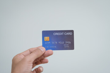 A close-up of a man&rsquo;s hand holding a bank credit card against a white background, emphasizing secure online payment services and financial convenience for shopping and banking transactions
