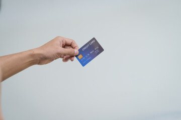 A close-up of a man’s hand holding a bank credit card against a white background, emphasizing secure online payment services and financial convenience for shopping and banking transactions