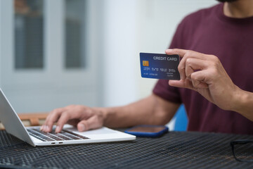 Close-up of a man's hand holding a bank credit card, highlighting online services for lending and...