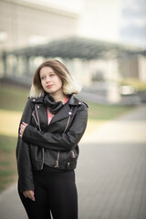 Portrait of a young beautiful girl in a black jacket in an urban environment.