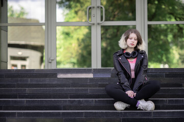 Portrait of a young beautiful girl in a black jacket in an urban environment.