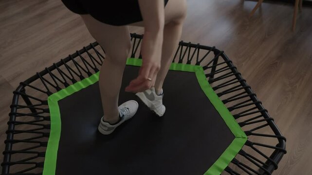 Woman exercising on a sports trampoline at home, focusing on fitness and fun. The trampoline setup is ideal for indoor workouts and healthy living.