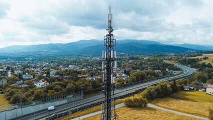 High cell tower with rural town and highway view.