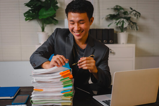 A businessman sits at his desk, working late into the night on his laptop. He reviews documents carefully, showcasing commitment and diligence as he works overtime to meet deadlines