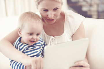 Home, mom and smile with toddler on tablet on sofa for streaming cartoons and online videos. People, parent and happy with kid on internet for educational games and entertainment for child growth