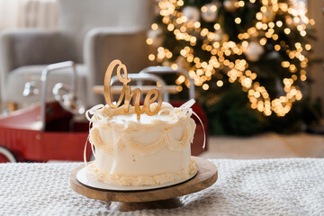 Elegant First Birthday Cake with Golden Topper Surrounded by Holiday Decor