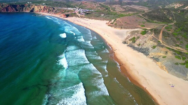 Drone shot over Praia de Odeceixe beach with coastal hills and sea view at sunset
