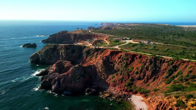 Drone shot over Praia de Odeceixe beach with coastal hills and sea view at sunset