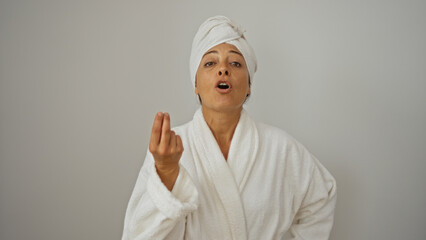 Woman in bathrobe gesturing and speaking isolated on white background, presenting a middle-aged brunette hispanic mature person with a towel on head.