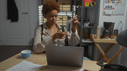 African american woman detective analyzing evidence in police station office.