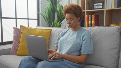 African american woman working on laptop at home in a cozy living room setting